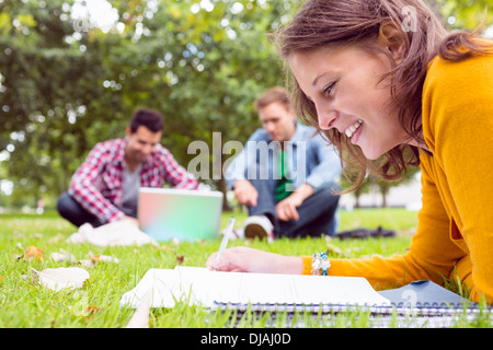 Studente iscritto note con due utilizzando laptop in posizione di parcheggio Foto Stock