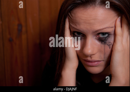 Giovane donna con il suo capo nelle sue mani e il suo make-up è in esecuzione da piangere. Foto Stock