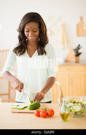 Nero donna tritare verdure in cucina Foto Stock