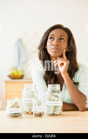 Nero donna mettere soldi in vasi di risparmio Foto Stock