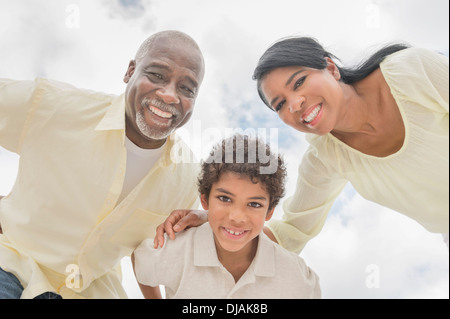 Tre generazioni della famiglia sorridente in huddle all'aperto Foto Stock