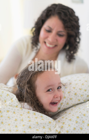 Razza mista madre figlia mettendo a letto Foto Stock