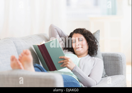 Razza mista donna lettura sul divano Foto Stock