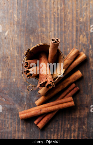 Bastoncini di cannella nella benna su sfondo di legno Foto Stock