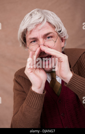 Capelli grigi uomo vecchio con le sue mani per amplificare la sua voce. Foto Stock