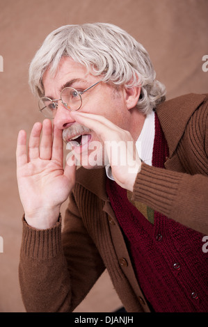 Capelli grigi uomo vecchio con le sue mani per amplificare la sua voce. Foto Stock