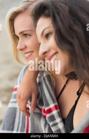 Due giovani donne coperte con coperta in spiaggia Foto Stock