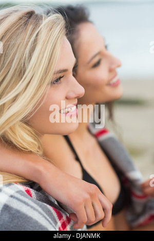 Due giovani donne coperte con coperta in spiaggia Foto Stock