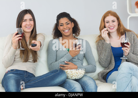 Happy amici con bicchieri di vino e popcorn godendo di un film a casa Foto Stock