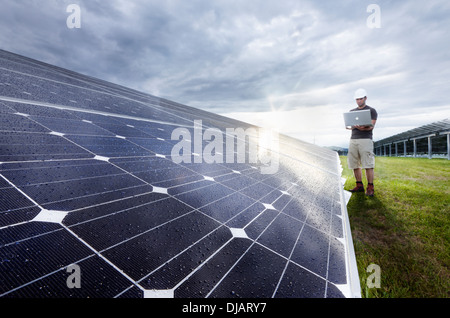 Installazione solare di controllo tecnico di pannelli solari con il suo computer portatile Foto Stock