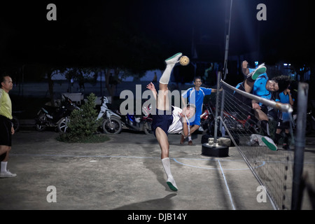 Atletismo estreme durante una partita notturna di Sepak Takraw. Tradizionale e Thai popolare gioco di calcio. Thailandia SUDEST ASIATICO Foto Stock