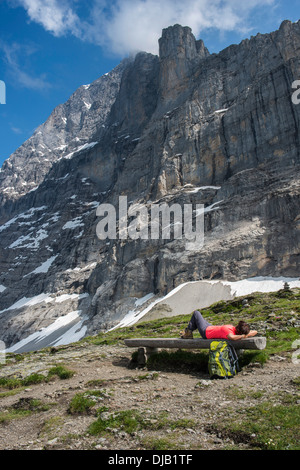 Un escursionista giacente su un banco di lavoro sull'Eiger Trail, dietro l'Eiger North Face, Alpi svizzere Jungfrau-Aletsch Patrimonio Mondiale UNESCO Foto Stock