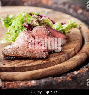 Arrosto di manzo sul tagliere con lattuga Foto Stock