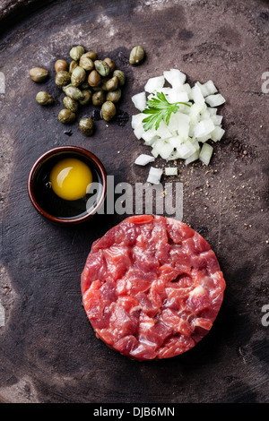 Tartara di manzo con capperi e cipolle fresche su sfondo scuro Foto Stock