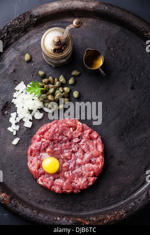 Tartara di manzo con capperi e cipolle fresche sul nero testurizzato sfondo Foto Stock