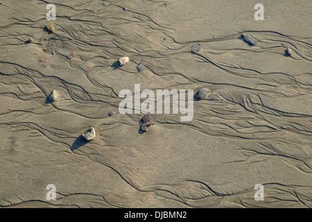 Primo piano di rivoli e ciottoli a bassa marea su una spiaggia di sabbia. South Devon, Regno Unito Foto Stock