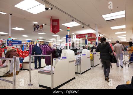 I clienti che passa attraverso il self-service area check-out al supermercato Tesco. Foto Stock