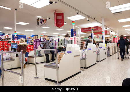 I clienti che passa attraverso il self-service area check-out al supermercato Tesco. Foto Stock