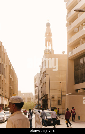 Gli uomini arabi attraversando la strada mentre il sole tramonta dietro il minareto di Ali Bin Abi Talib moschea di Bur Dubai. Dubai, EAU. Foto Stock