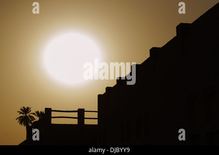 Il sole tramonta dietro uno spesso strato di sabbia nell'orizzonte di Sheikh Saeed Al-Maktoum House di silhouette. Dubai, EAU. Foto Stock