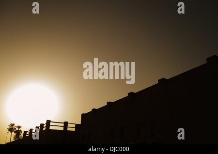 Il sole tramonta dietro uno spesso strato di sabbia nell'orizzonte di Sheikh Saeed Al-Maktoum House di silhouette. Dubai, EAU. Foto Stock