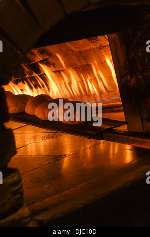 Un cuoco rimuove appena fatti flatbread arabi dalle fiamme di un forno esterno presso la famosa Kan Zaman ristorante. Dubai, EAU. Foto Stock