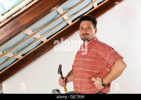 L'uomo facendo muretti a secco di lavorare sotto una pendenza del tetto Foto Stock