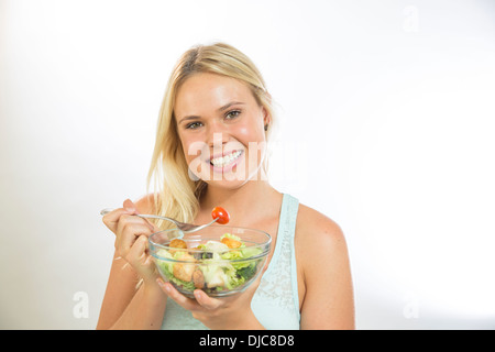 Giovane donna di mangiare insalata Foto Stock