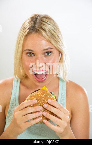 Giovane donna di mangiare hamburger Foto Stock