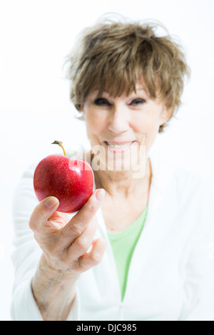 Donna matura tenendo su red apple Foto Stock