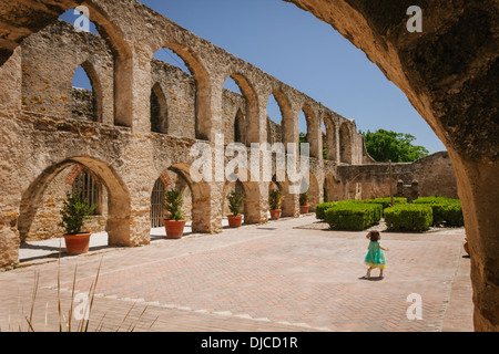 Bambina che corre attraverso il cortile centrale colonnato e presso la missione di San Jose. San Antonio, Texas. Foto Stock