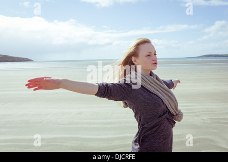 Donna attraente aprendo le braccia davanti all'oceano Foto Stock