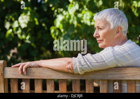 Malinconici anziani donna seduta da sola su un banco di lavoro Foto Stock