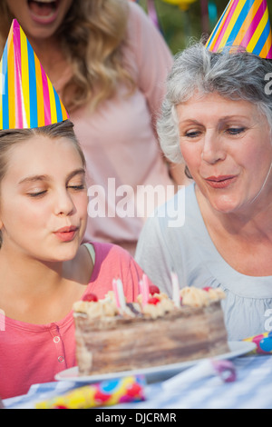 Ravvicinata di una giovane ragazza e sua nonna candele di soffiatura Foto Stock