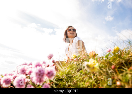 Donna seduta nel campo dei fiori selvatici Foto Stock