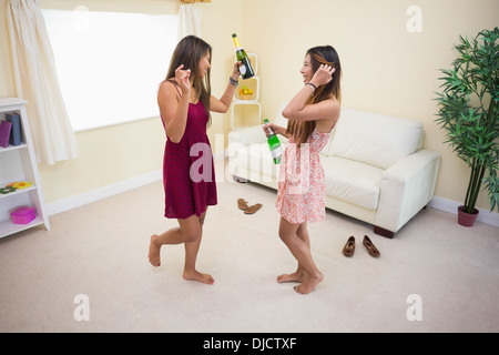 Due donne ballare e bere bottiglie di champagne Foto Stock