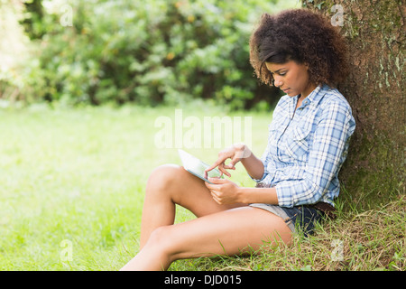 Gorgeous Brunette pacifica appoggiata contro la struttura tramite il tablet Foto Stock