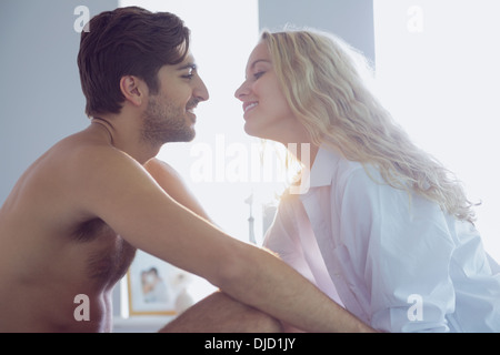 Allegro coppia giovane seduto sul loro letto Foto Stock