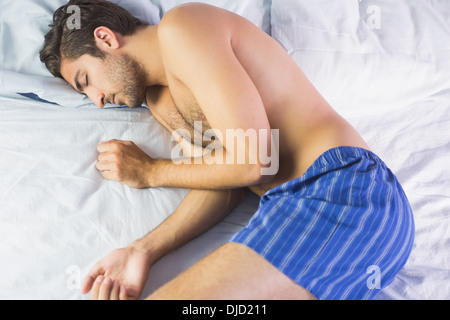 Giovane uomo sdraiato sul letto Foto Stock