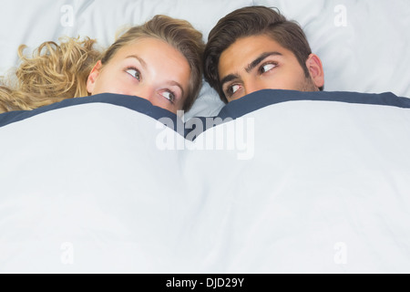 Bella donna che si nasconde sotto una coperta con il suo fidanzato Foto Stock