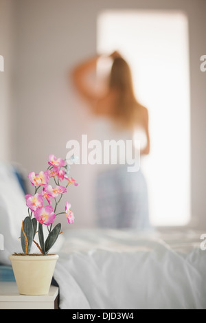 Focus sul delicato fiore rosa in un vaso sul comodino Foto Stock