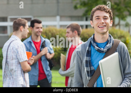 Allegro studente sorridente alla fotocamera nella parte anteriore dei suoi compagni di classe Foto Stock