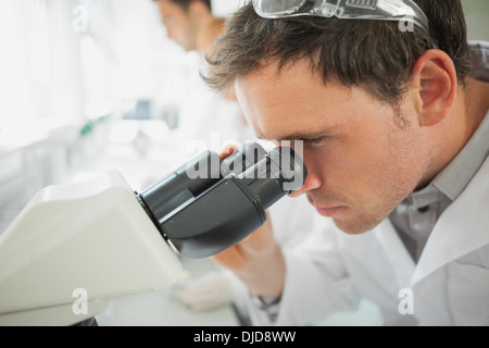 Giovane maschio scienziato guardando attraverso un microscopio Foto Stock