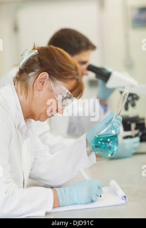 Attraente donna scienziato scrivendo su una clipboard Foto Stock