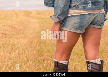 La sezione centrale della donna in denim shorts e stivali al campo di cereali Foto Stock