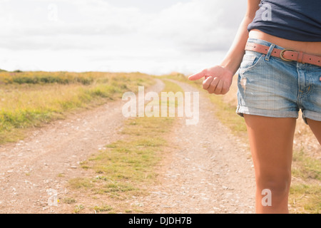 La sezione centrale della donna autostop su sterrato strada di campagna Foto Stock