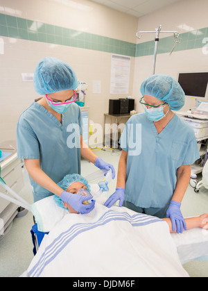 Gli infermieri regolando le maschere di ossigeno sul paziente femmina Foto Stock