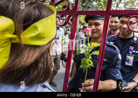 Bangkok, Tailandia. 27 Nov, 2013. Governo anti-manifestanti fiori a mano al Royal Thai funzionari di polizia presso il Royal Thai Questura su Rama I Road di Bangkok. Manifestanti hanno costretto la evacuazione della Thailandia del top di lotta al crimine agenzia, il quarto giorno di manifestazioni di piazza. I dimostranti che chiedono al governo di step-down, mirata di un complesso di uffici governativi al di fuori della citta'. La protesta del leader hanno detto che volevano arrestare ministeri del governo nel tentativo di causare perturbazioni. Essi accusano il governo di essere controllata dal primo ministro del fratello, Thaksin Shinawatra. (Cr Foto Stock