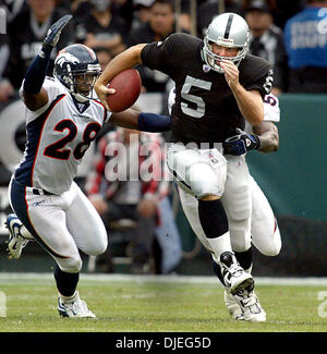 Oct 17, 2004; Oakland, CA, Stati Uniti d'America; NFL Football: Kerry Collins ottenere azionato verso il basso da Bronco tacklers #59 Donnie Spragan e (sinistra) #29 Kenroy Kennedy per un sacco nel secondo trimestre. Foto scattata durante i raider vs Broncos gioco presso la Network Associates Coliseum. Foto Stock
