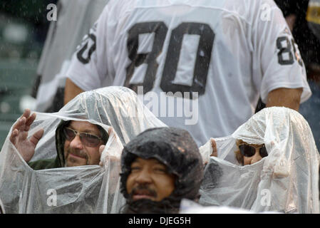 Oct 17, 2004; Oakland, CA, Stati Uniti d'America; NFL Football: Raider fans Edward Eggiman e sua moglie Patty provare e conservare in un luogo asciutto durante un Raider. Foto scattata durante i raider vs Broncos gioco presso la Network Associates Coliseum. Foto Stock